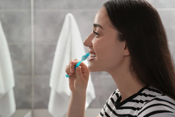 年轻女子在浴室用塑料牙刷刷牙 — 图库照片