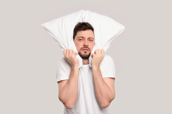 Κουρασμένος Άνθρωπος Καλύπτει Αυτιά Μαξιλάρι Ανοιχτό Γκρι Φόντο Πρόβλημα Αϋπνίας — Φωτογραφία Αρχείου