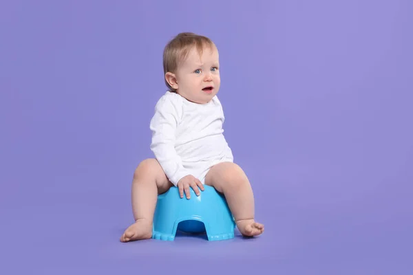 stock image Little child sitting on baby potty against violet background