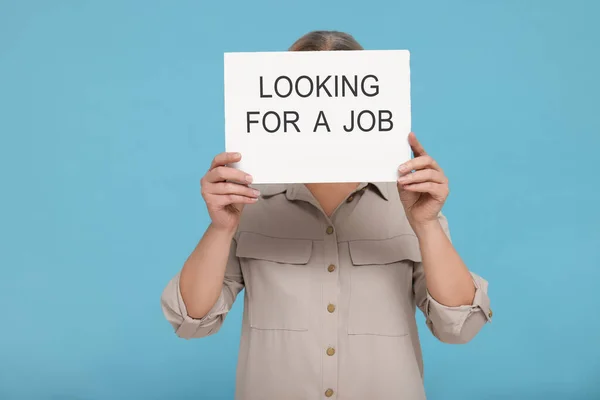 拿着印有 寻找蓝绿色背景工作 字样的硬纸板标志的失业妇女 — 图库照片