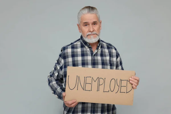 Senior Man Håller Pappskylt Med Ord Arbetslös Ljusgrå Bakgrund — Stockfoto