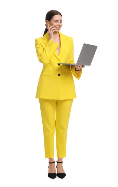 白い背景にスマートフォンで話してノートパソコンと黄色のスーツの美しいビジネス女性 — ストック写真