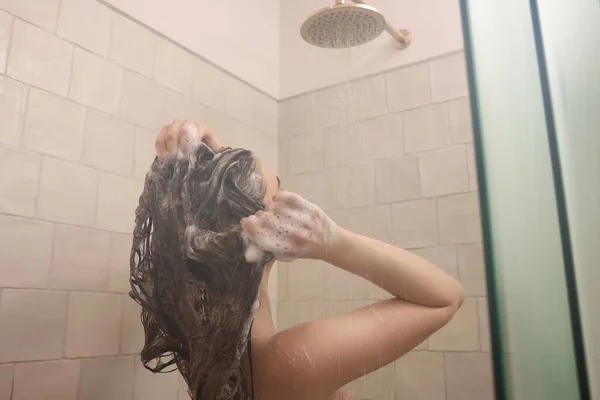 自宅でシャワーを浴びながら髪を洗う若い女性 — ストック写真