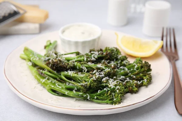 Stock image Tasty cooked broccolini with cheese, lemon and sauce on table, closeup