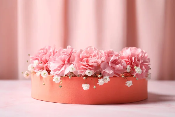 ピンクの大理石のテーブルの上のオレンジ色の丸いスタンド ジプシーとカーネーションの花 クローズアップ 製品のためのスタイリッシュなプレゼンテーション — ストック写真