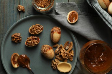 Taze pişirilmiş ev yapımı ceviz şekilli kurabiyeler fındıklı ve kaynamış süt ahşap masada, düz yatıyordu.