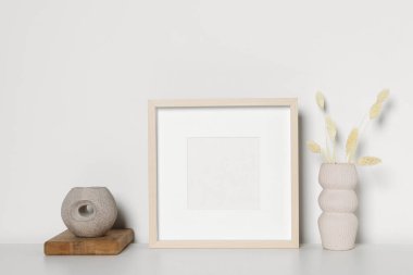 Boş fotoğraf çerçevesi ve vazo. Beyaz masa üzerinde kuru dekoratif çiviler var. Tasarım için model