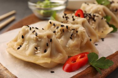 Lezzetli gyoza (Asya hamur köftesi) susam tohumları ve ahşap tahtada kırmızı biber, yakın plan