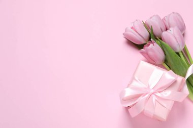 Pembe arka planda fiyonklu ve laleli güzel bir hediye kutusu var. Metin için boşluk