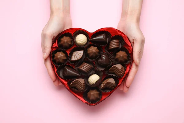 Женщина Держит Коробку Форме Сердца Вкусными Шоколадными Конфетками Розовом Фоне — стоковое фото