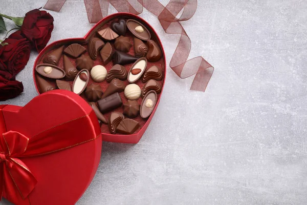 Hjärtformad Ask Med Läckra Chokladgodis Rosor Och Band Ljusgrått Bord — Stockfoto