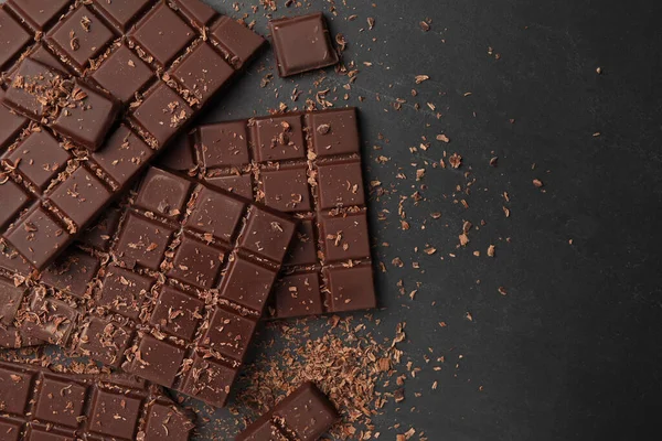 Stock image Pieces and shavings of tasty chocolate bars on grey table, flat lay. Space for text