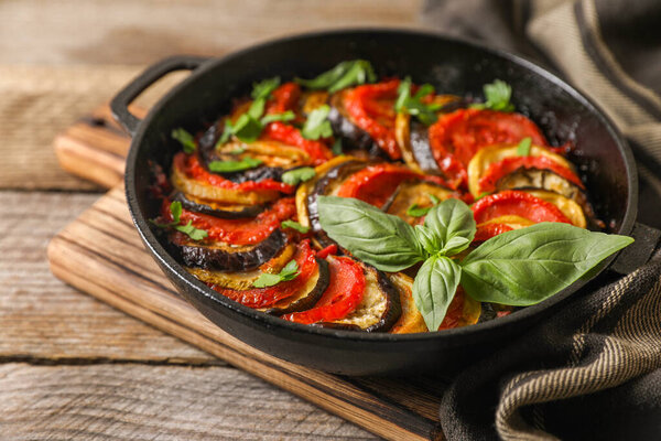 Delicious ratatouille in frying pan on wooden table, closeup