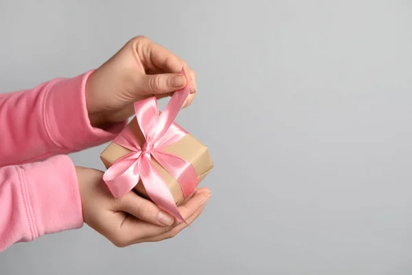 女人拿着粉红的礼品盒 背景浅灰 案文的篇幅 — 图库照片