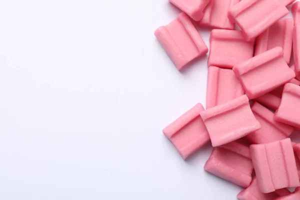 Tasty pink chewing gums on white background, flat lay. Space for text