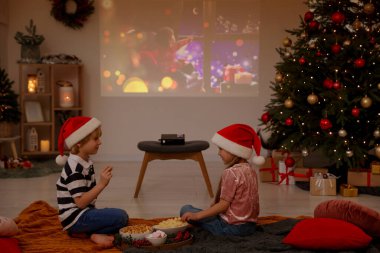 Erkek ve kız kardeş odada video projektörünün yanında vakit geçiriyorlar. Noel atmosferi