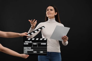 Aktris sahnedeyken ikinci asistan kamera siyah arka planda el çırpma tahtası tutuyor. Film endüstrisi