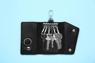 Leather holder with keys on light blue background, top view