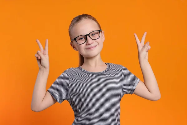 Porträtt Söt Flicka Glasögon Som Visar Seger Gest Orange Bakgrund — Stockfoto