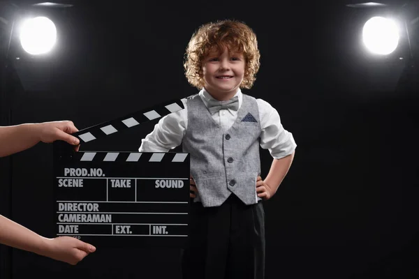 Uśmiechnięty Chłopak Występujący Podczas Drugiej Asystentki Aparatu Trzymającej Klapkę Scenie — Zdjęcie stockowe