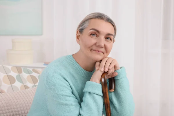 老妇人 拿着手杖坐在家里的沙发上 — 图库照片