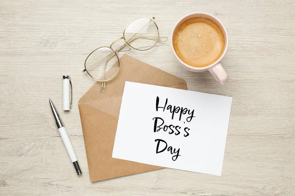Card with phrase Happy Boss`s Day, envelope, coffee, glasses and pen on wooden table, flat lay