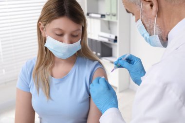 Doktor klinikteki hastaya hepatit aşısı veriyor.