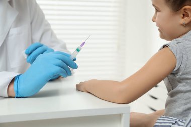 Çocuk hepatit aşısı. Doktor klinikteki küçük kıza iğne yapıyor.