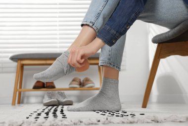 Woman putting on grey socks at home, closeup