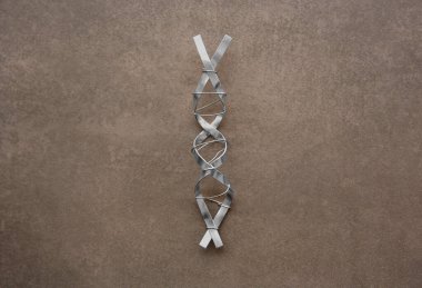 Kahverengi arka planda metalden yapılmış DNA molekül modeli, üst görünüm