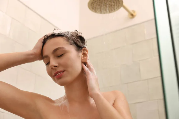 年轻女人在家里洗澡的时候洗头 — 图库照片