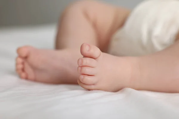 stock image Cute little baby in diaper on bed, closeup