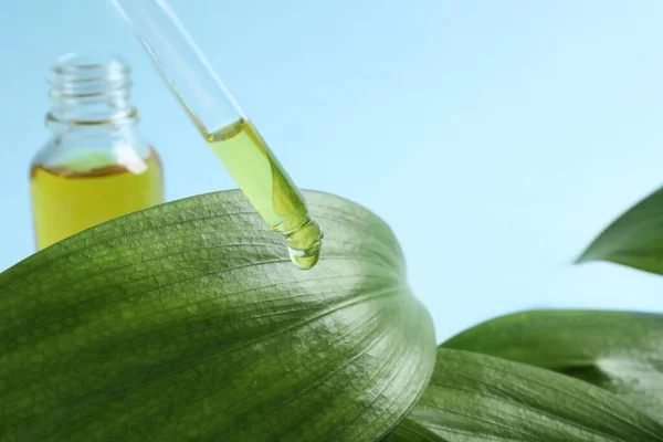 Droppande Kosmetisk Olja Från Pipett Grönt Löv Ljusblå Bakgrund Närbild — Stockfoto