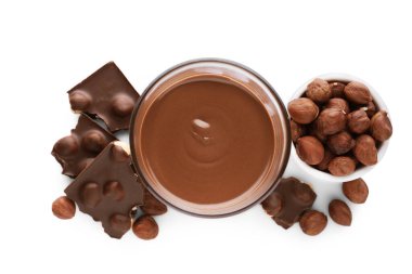 Çikolata parçaları, bir bardak lezzetli macun ve beyaz arka planda fındık.