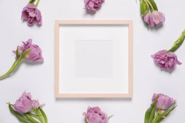 Boş fotoğraf çerçevesi ve beyaz arka planda güzel çiçekler. Tasarım için boşluk