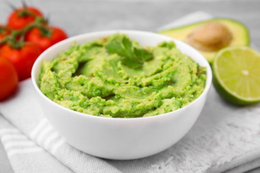 Bir kase lezzetli guacamole ve kumaş üzerine malzemeler.