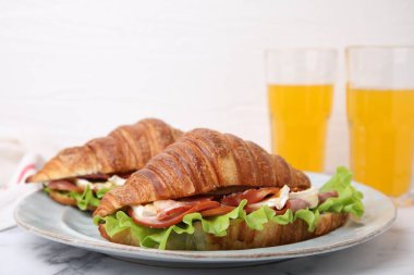 Krem peynirli lezzetli kruvasanlar, beyaz mermer masada jambon ve pastırma, yakın plan.