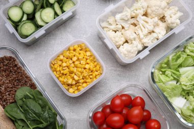 Cam ve plastik kaplar açık gri masada farklı taze ürünler, düz konteynırlar.