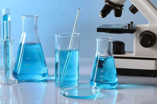 Vidros Laboratório Diferentes Com Líquido Azul Claro Microscópio Mesa — Fotografia de Stock