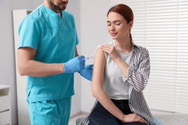 Doktor klinikteki hastaya hepatit aşısı veriyor.