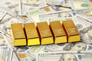 Many shiny gold bars on dollar banknotes