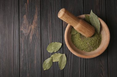 Havan mermisi, ahşap masanın üzerinde aromatik defne yaprakları ve düz bir şekilde yatar. Metin için boşluk