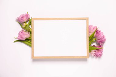 Boş fotoğraf çerçevesi ve beyaz arka planda güzel çiçekler, üst manzara. Tasarım için boşluk