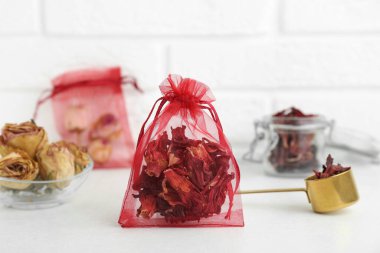 Beyaz masanın üzerinde kurumuş amber çiçekleri olan kese.