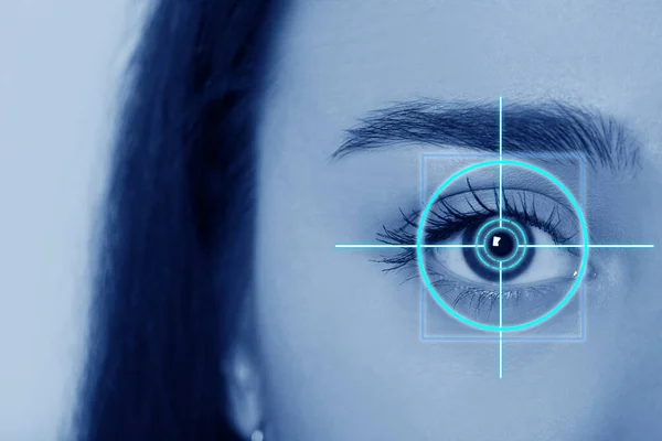 Vision test. Laser reticle focused on woman's eye, closeup. Light blue tone effect