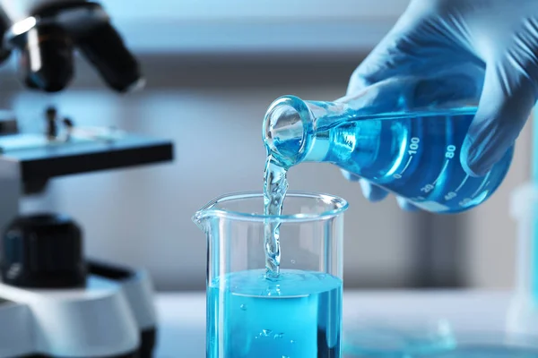 플라스크에서 나오는 액체를 실험실의 비커에 과학자들 클로즈업 — 스톡 사진