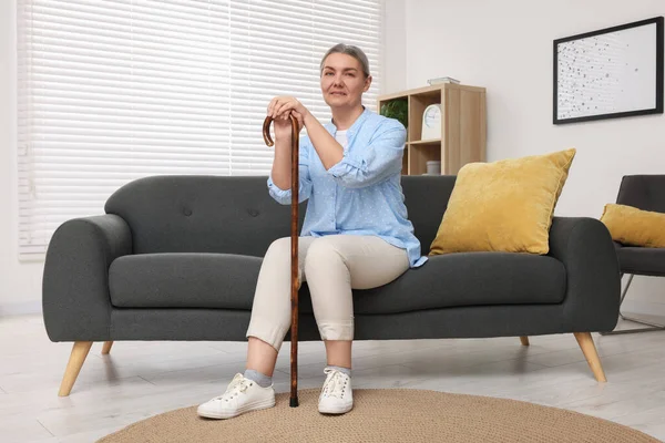 老妇人 拿着手杖坐在家里的沙发上 — 图库照片