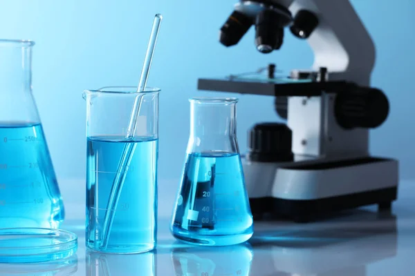 Verschillende Laboratoriumglaswerk Met Lichtblauwe Vloeistof Microscoop Tafel — Stockfoto