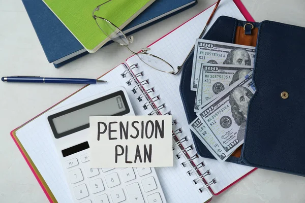 Card with phrase Pension Plan, dollar banknotes, calculator and notebooks on white office table, flat lay