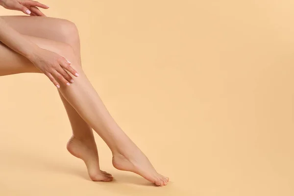 拥有漂亮光滑腿的女人 米色背景 案文的篇幅 — 图库照片